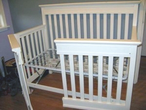 A crib frame with the front side divided in half like swinging French doors
